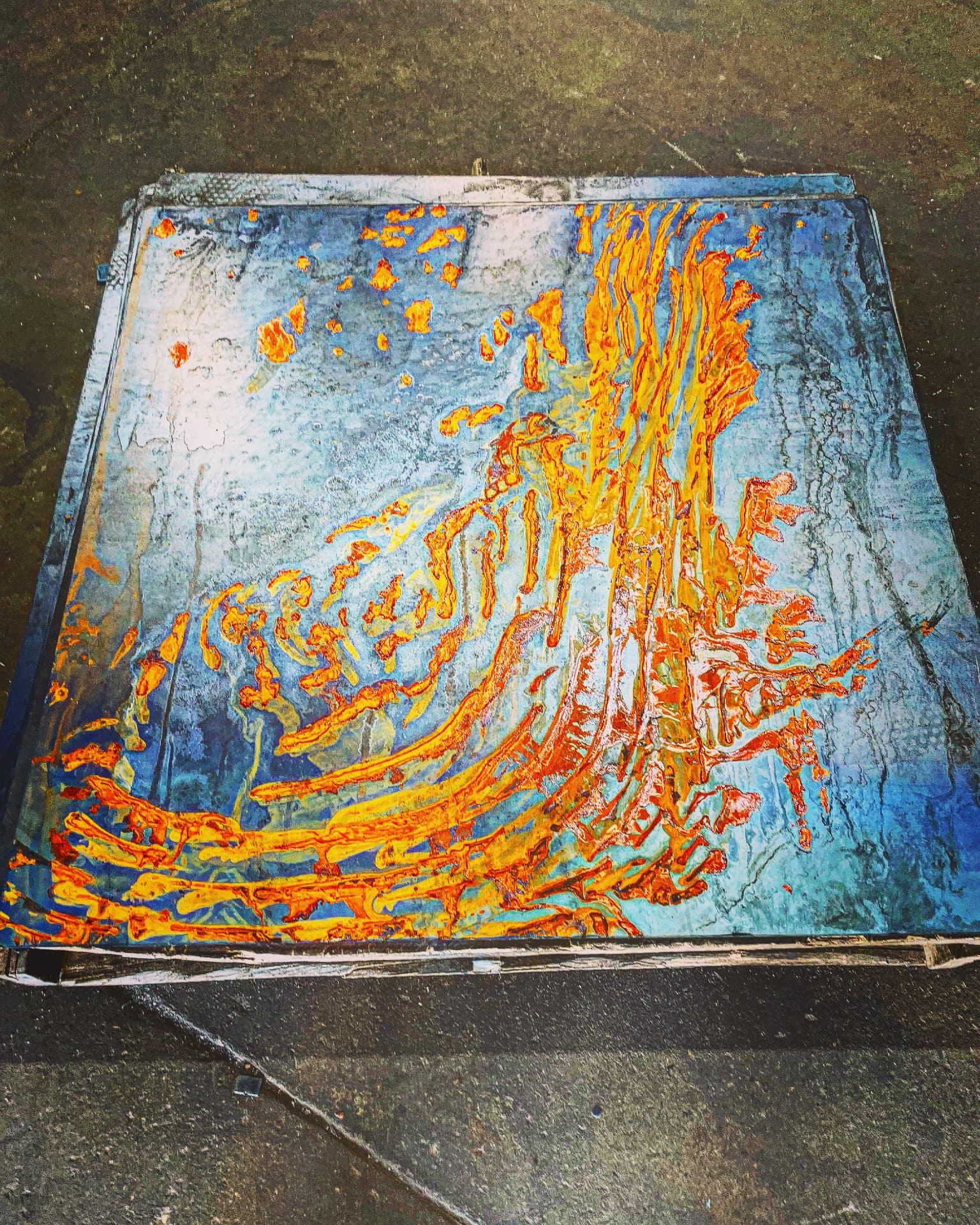 Abstract painted steel panel with thick orange and yellow streaks dragged across a blue and white ground